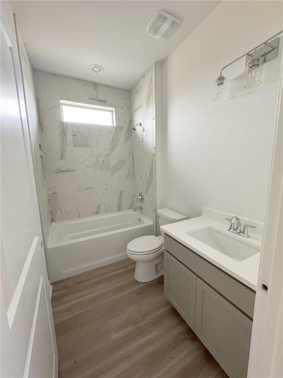 full bathroom with vanity, hardwood / wood-style floors, toilet, and tiled shower / bath