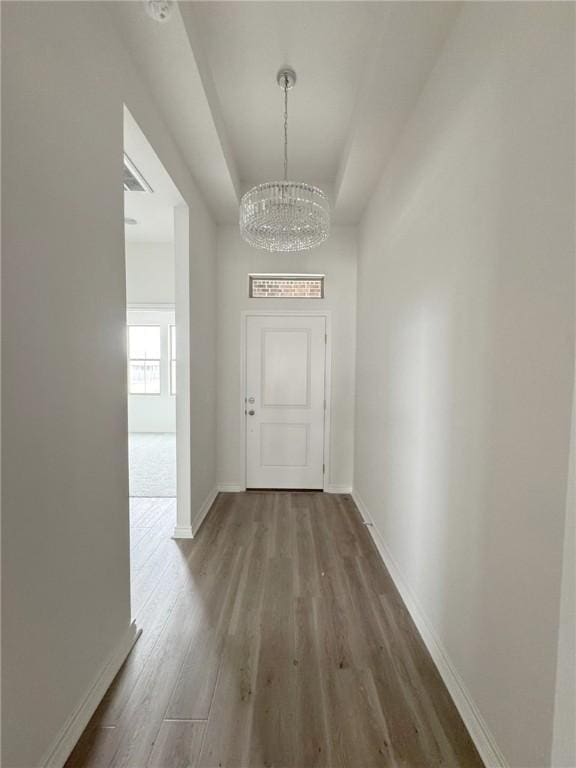 corridor featuring wood-type flooring and a chandelier