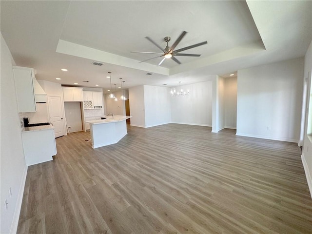 2550 Las Estrellas St, Corpus Christi, TX 78414 - unfurnished living room with a chandelier, ceiling fan, a raised ceiling, baseboards, and light wood-style flooring