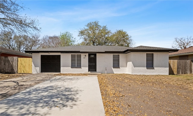 view of front of property featuring a garage, brick siding, driveway, and fence