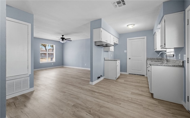 kitchen with visible vents, white cabinets, light wood-style flooring, and light stone countertops