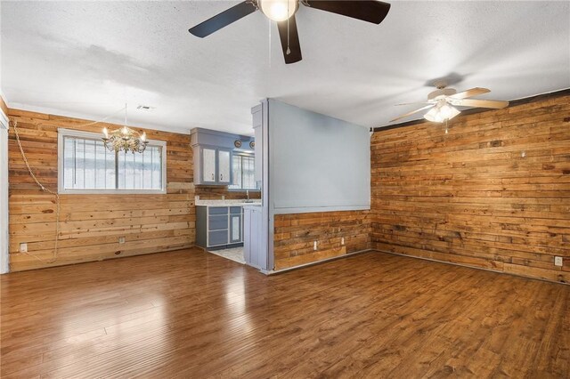 3718 Brushwood, Corpus Christi, TX 78415 - unfurnished living room featuring wooden walls, ceiling fan, a chandelier, wood finished floors, and a sink