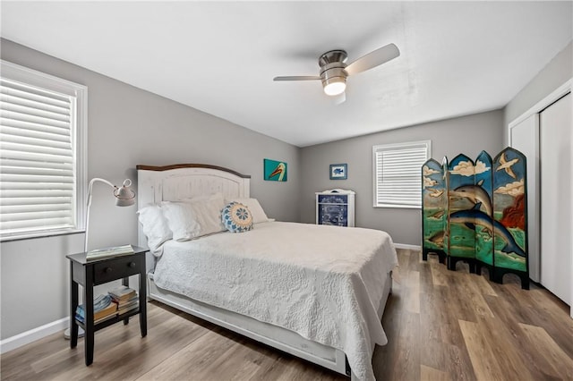 bedroom featuring a closet, wood finished floors, a ceiling fan, and baseboards