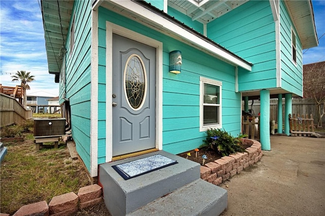 property entrance with central AC, fence, and a carport