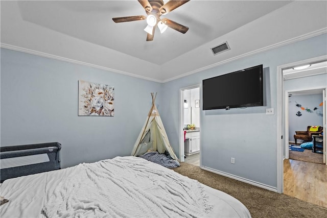 bedroom with vaulted ceiling, a tray ceiling, visible vents, and baseboards