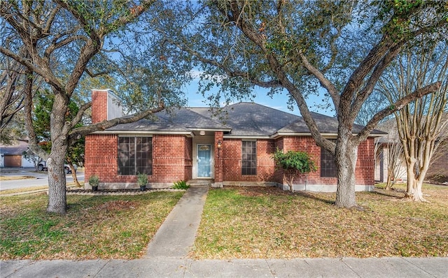 ranch-style house with brick siding, a chimney, and a front yard