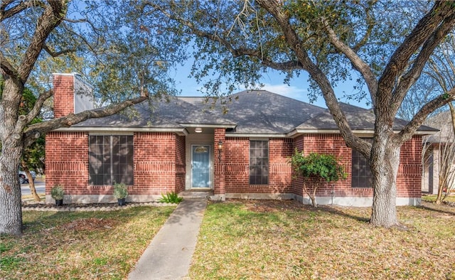 ranch-style house featuring brick siding, a chimney, and a front yard