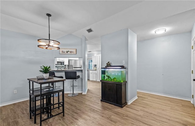 dining area with lofted ceiling, baseboards, visible vents, and wood finished floors