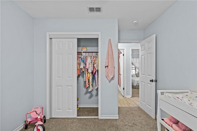 carpeted bedroom with a closet, visible vents, and baseboards