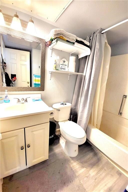 full bathroom with toilet, vanity, shower / bath combination with curtain, and hardwood / wood-style floors