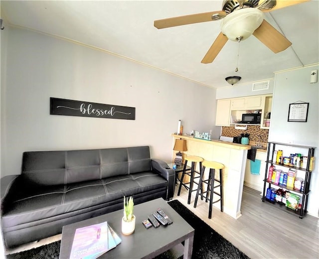 living room featuring light hardwood / wood-style floors, ceiling fan, and crown molding