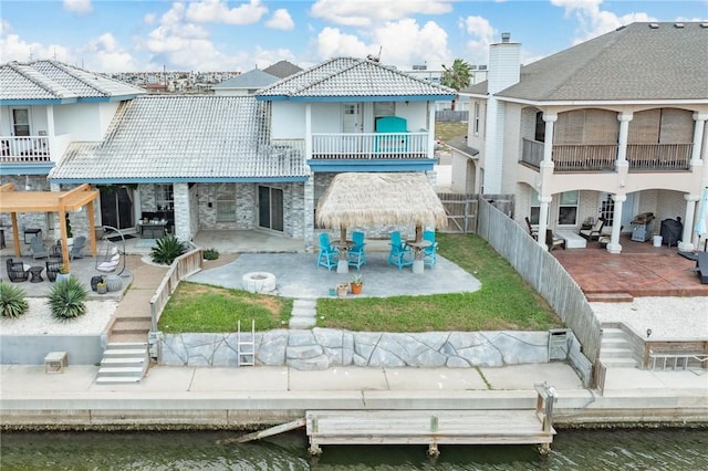 back of property with a water view, a balcony, and a patio