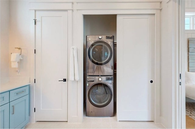 laundry room featuring stacked washer and clothes dryer and light tile patterned floors