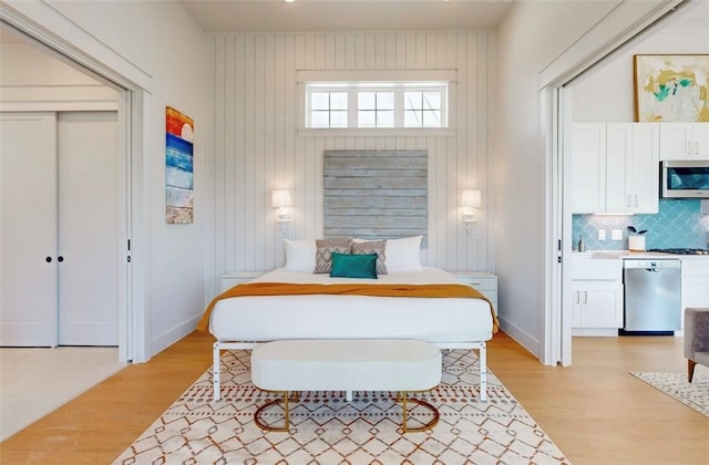 bedroom with light wood-type flooring, wooden walls, and a closet