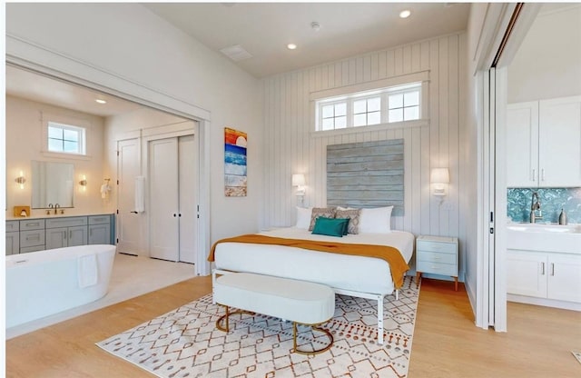 bedroom with multiple windows, sink, and light hardwood / wood-style floors