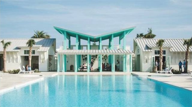 back of house with a community pool and a patio area