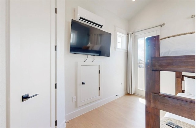 interior space with light hardwood / wood-style floors, lofted ceiling, and an AC wall unit