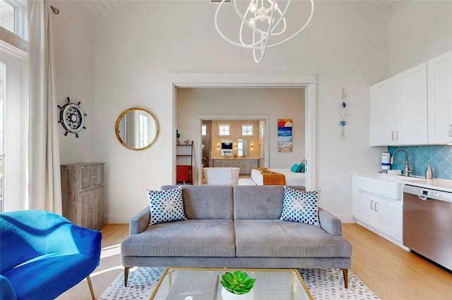 living room featuring a wealth of natural light, light hardwood / wood-style flooring, sink, and high vaulted ceiling