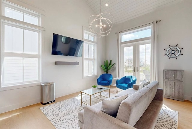 living room featuring light hardwood / wood-style floors, high vaulted ceiling, an inviting chandelier, and french doors