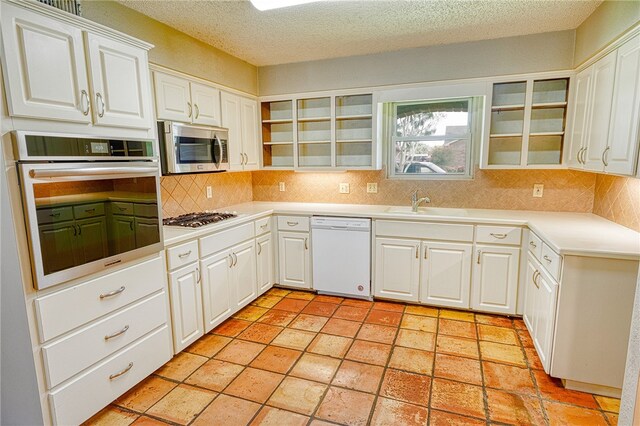 4513 Greensboro Dr, Corpus Christi, TX 78413 - kitchen with stainless steel appliances, backsplash, white cabinets, glass insert cabinets, and light countertops