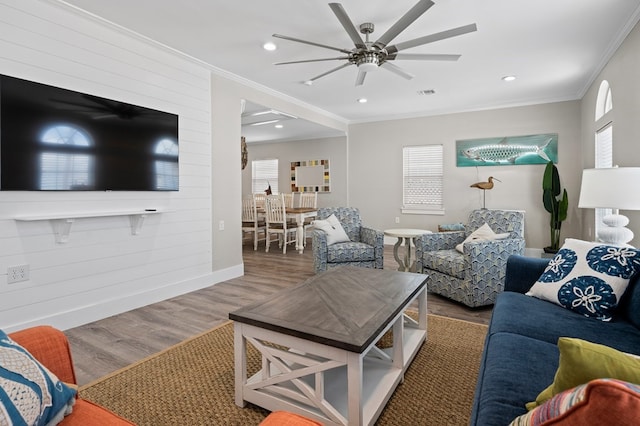 living room with crown molding, ceiling fan, and dark wood-type flooring