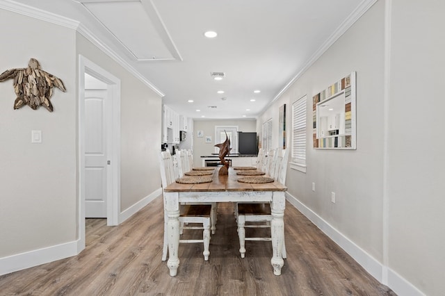 dining space featuring light wood-type flooring and crown molding