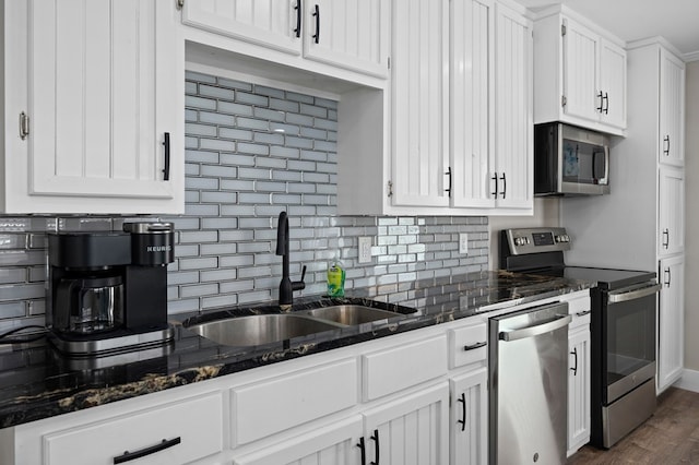 kitchen with white cabinetry, sink, dark hardwood / wood-style flooring, dark stone countertops, and appliances with stainless steel finishes