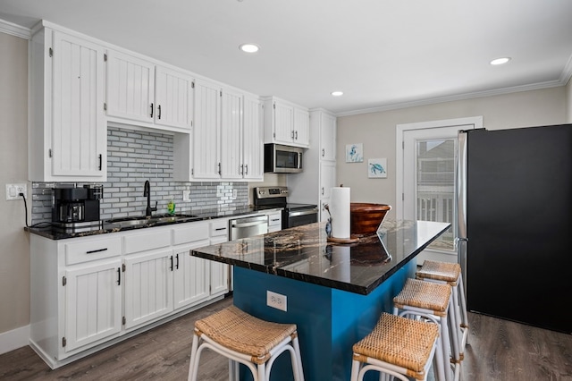 kitchen featuring a center island, white cabinets, sink, a breakfast bar area, and stainless steel appliances