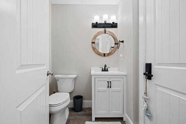 bathroom with hardwood / wood-style floors, vanity, and toilet