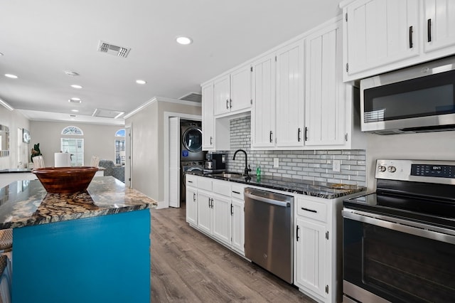 kitchen with white cabinetry, sink, stacked washer and clothes dryer, and appliances with stainless steel finishes