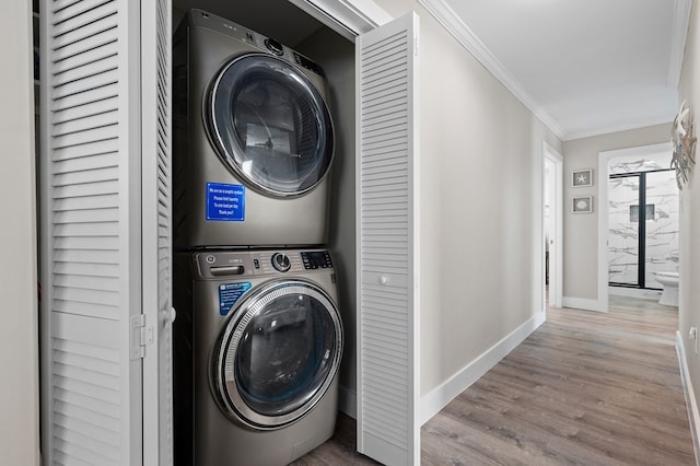 washroom with stacked washer and dryer, light wood-type flooring, and ornamental molding