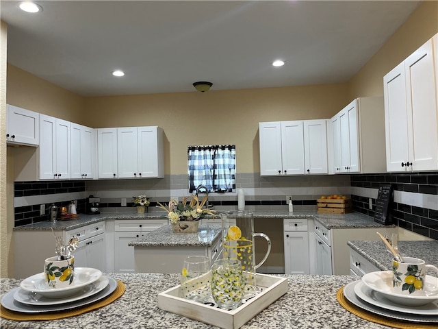 kitchen with light stone countertops and white cabinetry