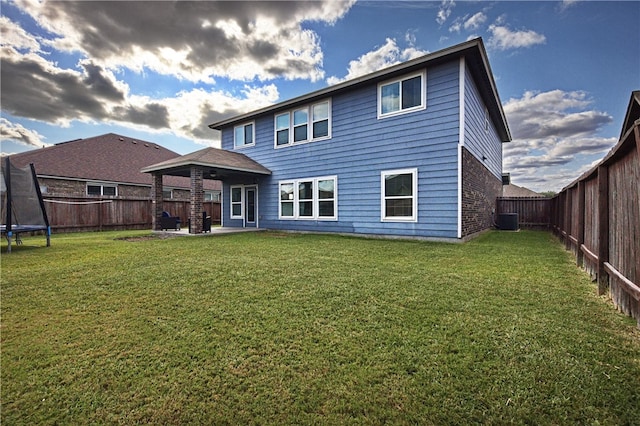 rear view of house with a patio, cooling unit, a yard, and a trampoline