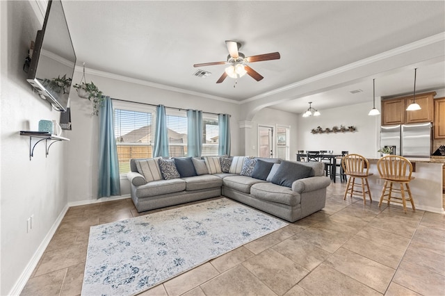 tiled living room with ceiling fan with notable chandelier and crown molding