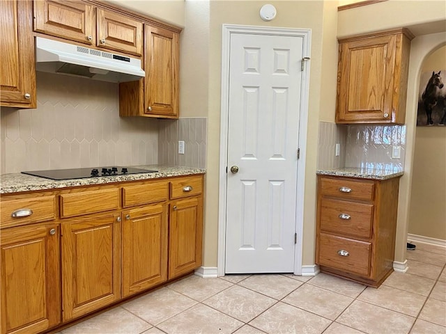 kitchen featuring under cabinet range hood, brown cabinets, and black electric stovetop