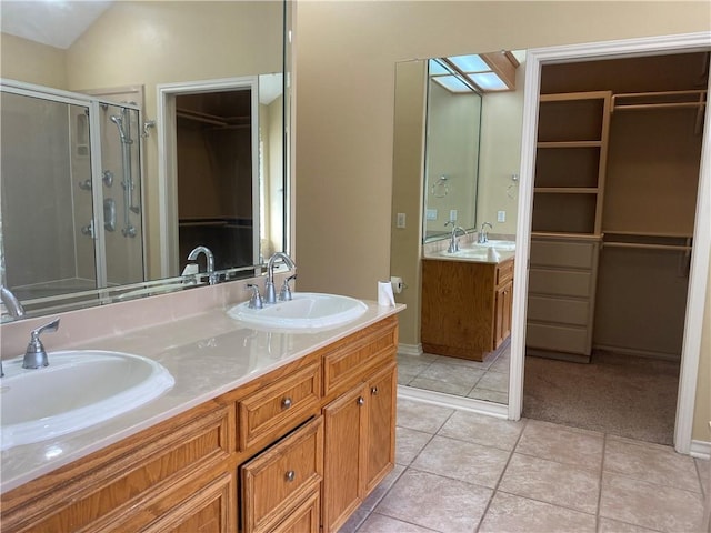 bathroom with double vanity, a stall shower, a walk in closet, and a sink