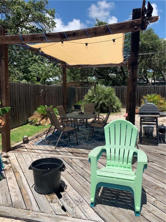 deck featuring outdoor dining area, a fenced backyard, and a grill