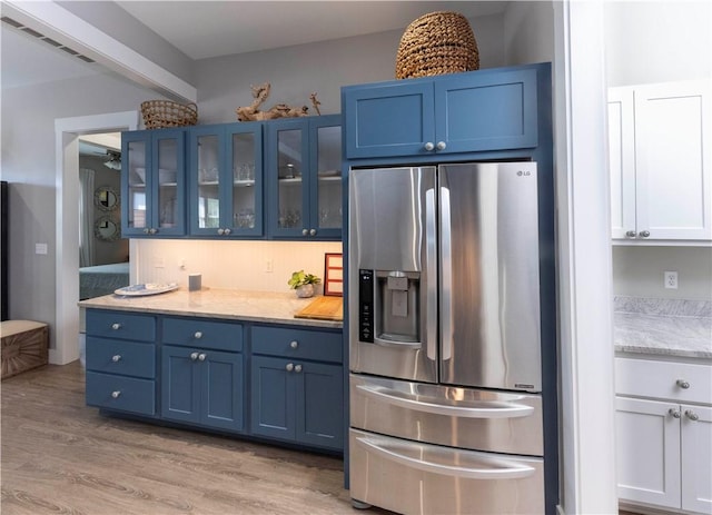 101 Boardwalk Ave, Rockport, TX 78382 - kitchen with stainless steel fridge with ice dispenser, visible vents, light wood-type flooring, and blue cabinets