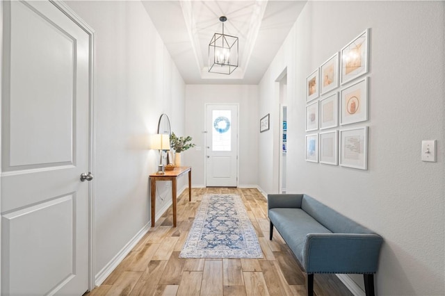 entryway with a notable chandelier, light wood-style flooring, and baseboards