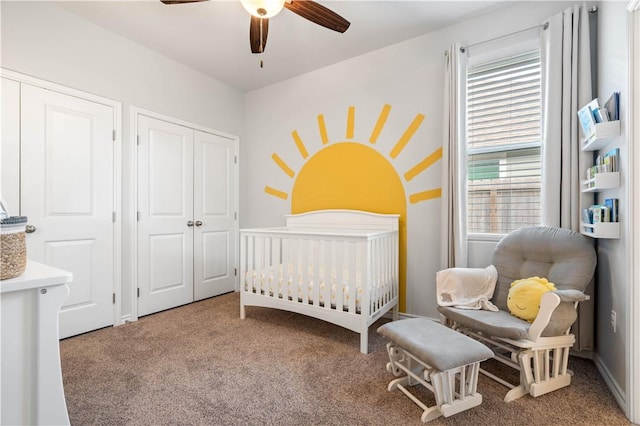 bedroom featuring a nursery area, carpet flooring, and a ceiling fan