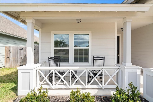 entrance to property with covered porch and fence