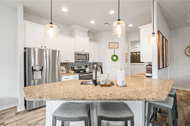 kitchen with white cabinets, appliances with stainless steel finishes, visible vents, and decorative backsplash