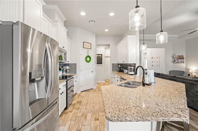 kitchen with a sink, visible vents, white cabinetry, open floor plan, and appliances with stainless steel finishes