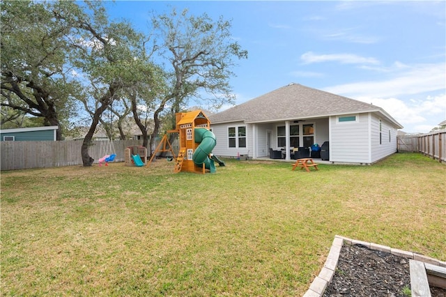 back of house featuring a fenced backyard, a shingled roof, a lawn, and a playground