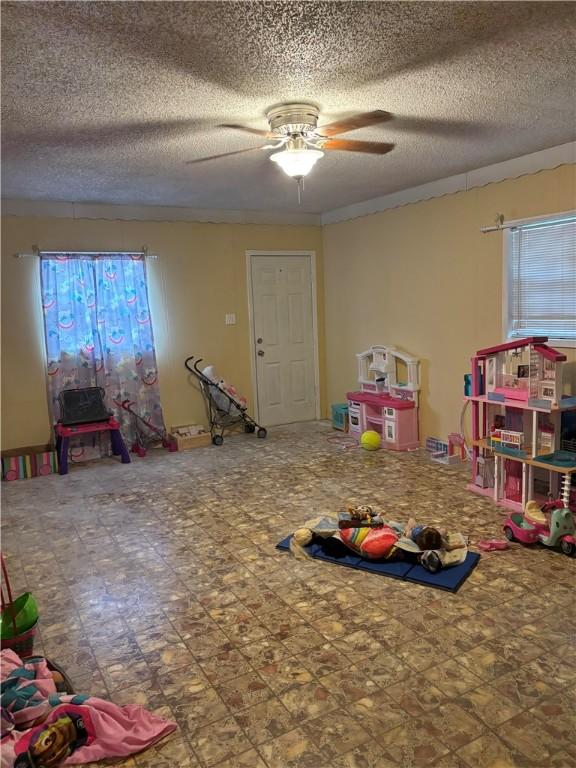 playroom with a textured ceiling and ceiling fan