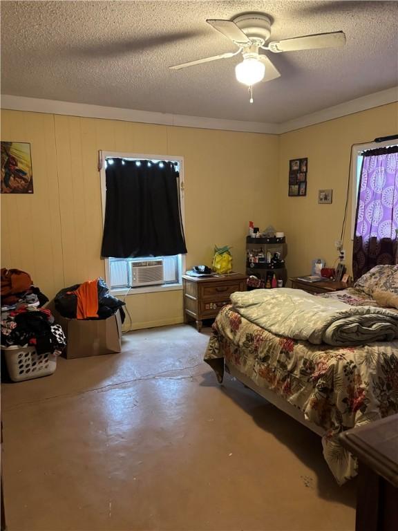 bedroom featuring cooling unit, a textured ceiling, ceiling fan, and concrete floors