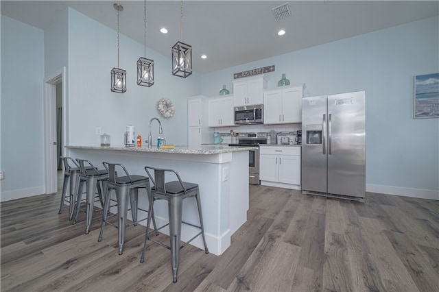 kitchen with white cabinetry, light wood-type flooring, appliances with stainless steel finishes, and a breakfast bar