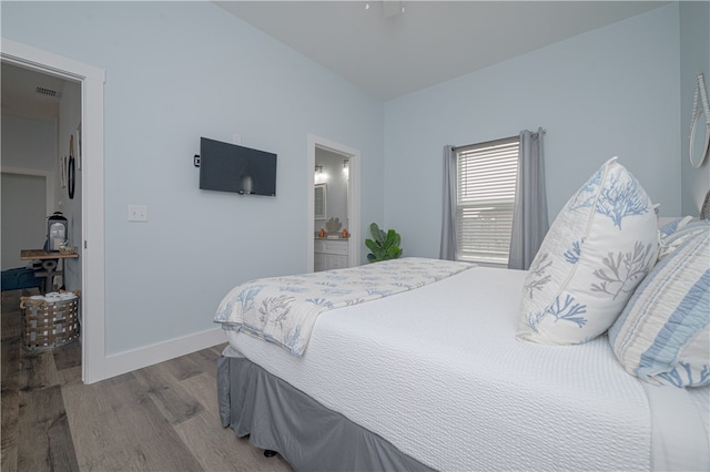 bedroom featuring connected bathroom and light hardwood / wood-style flooring