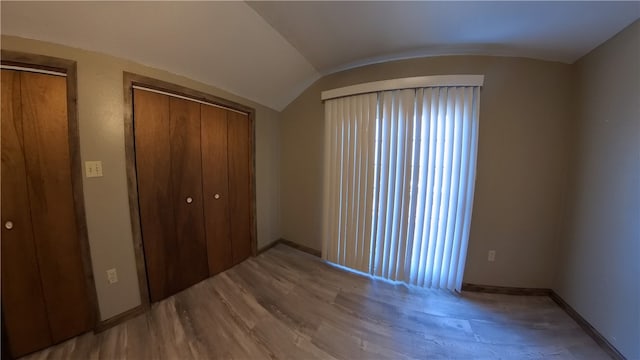 unfurnished bedroom with hardwood / wood-style floors and vaulted ceiling