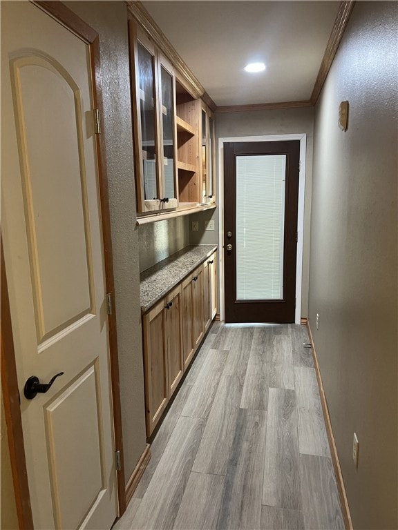 doorway featuring light wood-type flooring and crown molding